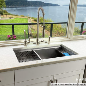 Undermount legacy advanced ledge stainless sink with drop in strainer and sponge caddy accesories overlooking a bay with mountains off in the distance 