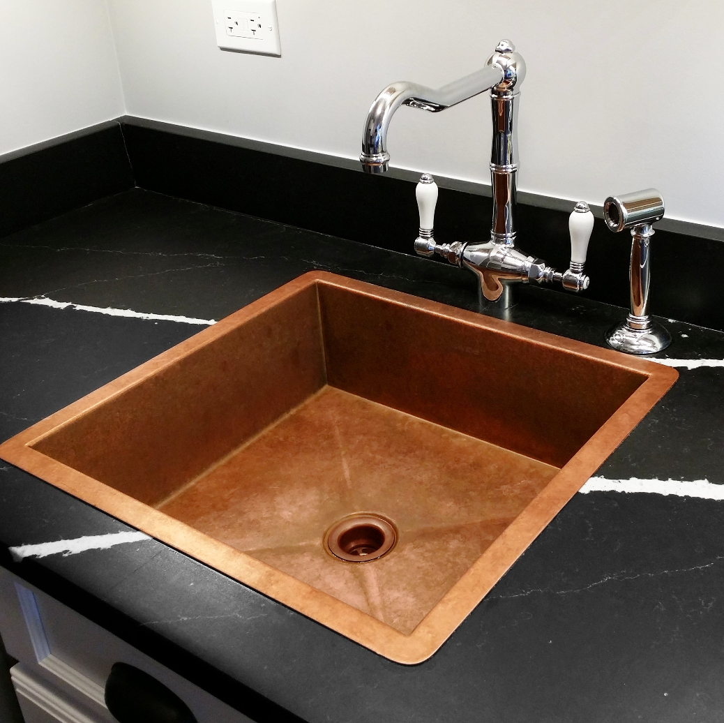 Pure copper kitchen sink in black countertop with bridge faucet, handcrafted in Florida