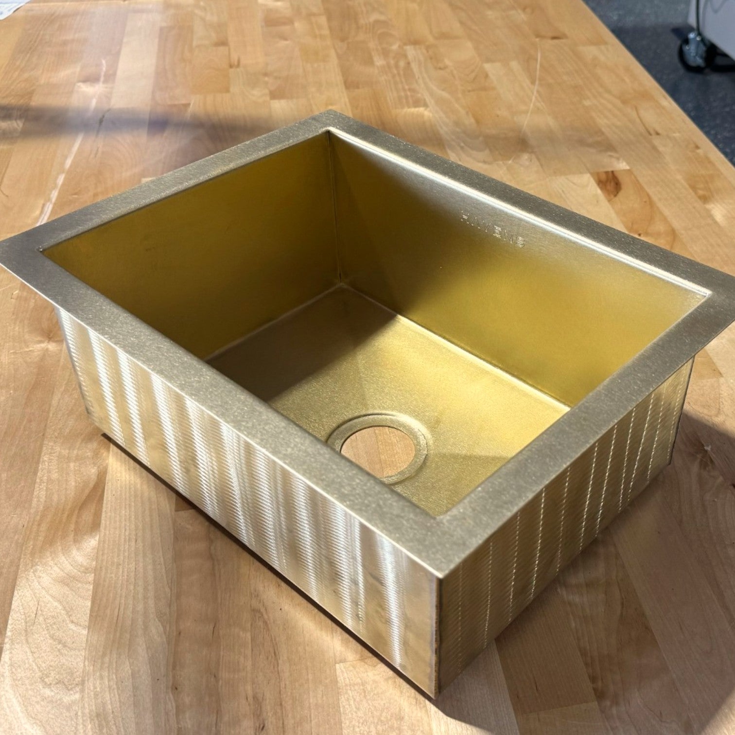 Handcrafted luxe brass small sink on a butcher block workbench, showing exterior and basin