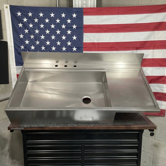 Full custom Stainless steel drain board Farmhouse sink on a stand with an American flag in the background. Made in USA