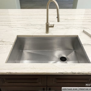 Undermount stainless steel kitchen sink under white granite countertops. Textured 16 gauge stainless steel