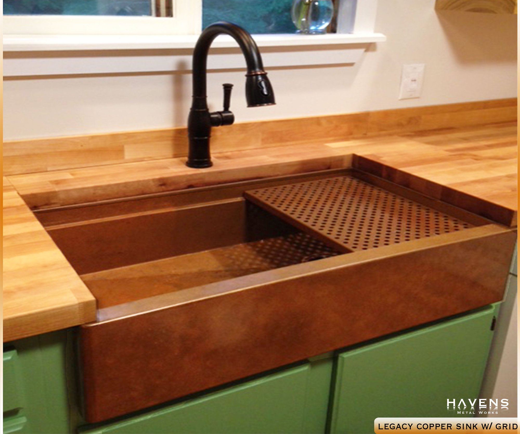 Legacy copper farm style kitchen sink installed as an undermount with a copper faucet.