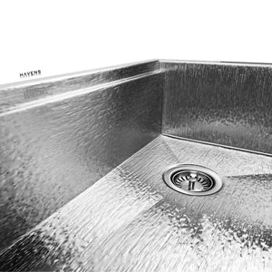 Product image of stainless steel 3.5" kitchen sink drain assembly installed in right rear corner of Havens Metal Sink in Royal Oak finish